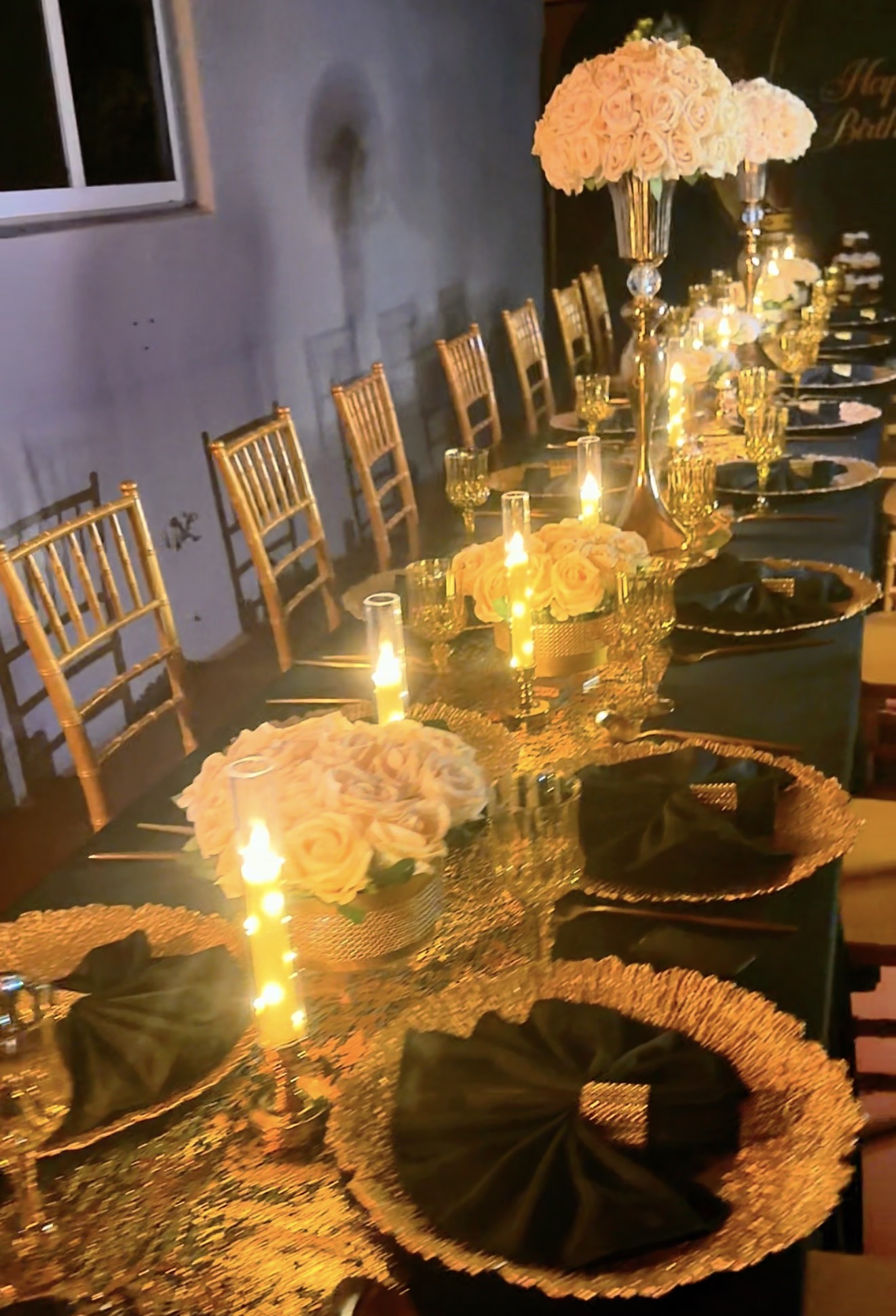 Black and gold Fine Rise tablescape with gold Chiavari chairs, floral centerpieces and candlelight
