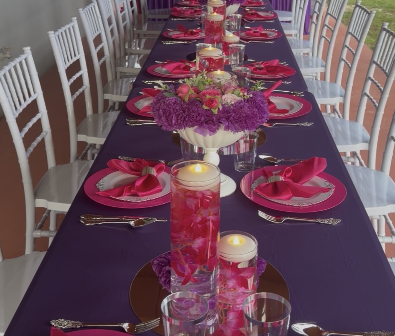 Purple and hot pink Fine Rise tablescape with white Chiavari chairs, florals and candle décor